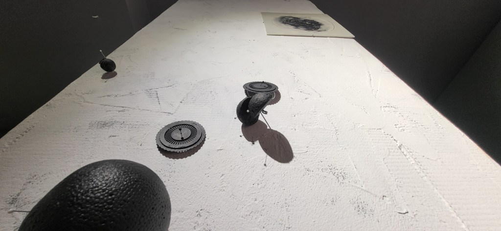 Roxana Donaldson, Saftey First art installation, Assemblage art black spheres, detail, 2025. Black porous sphere with pins, wires and nails on a white wall in official Safety First the Aftermath exhibtion, Bucharest, Galeria Calea Victoriei 91-93, 2025.